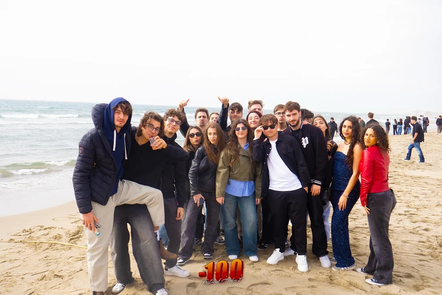 Grande gruppo di studenti in posa sulla sabbia.