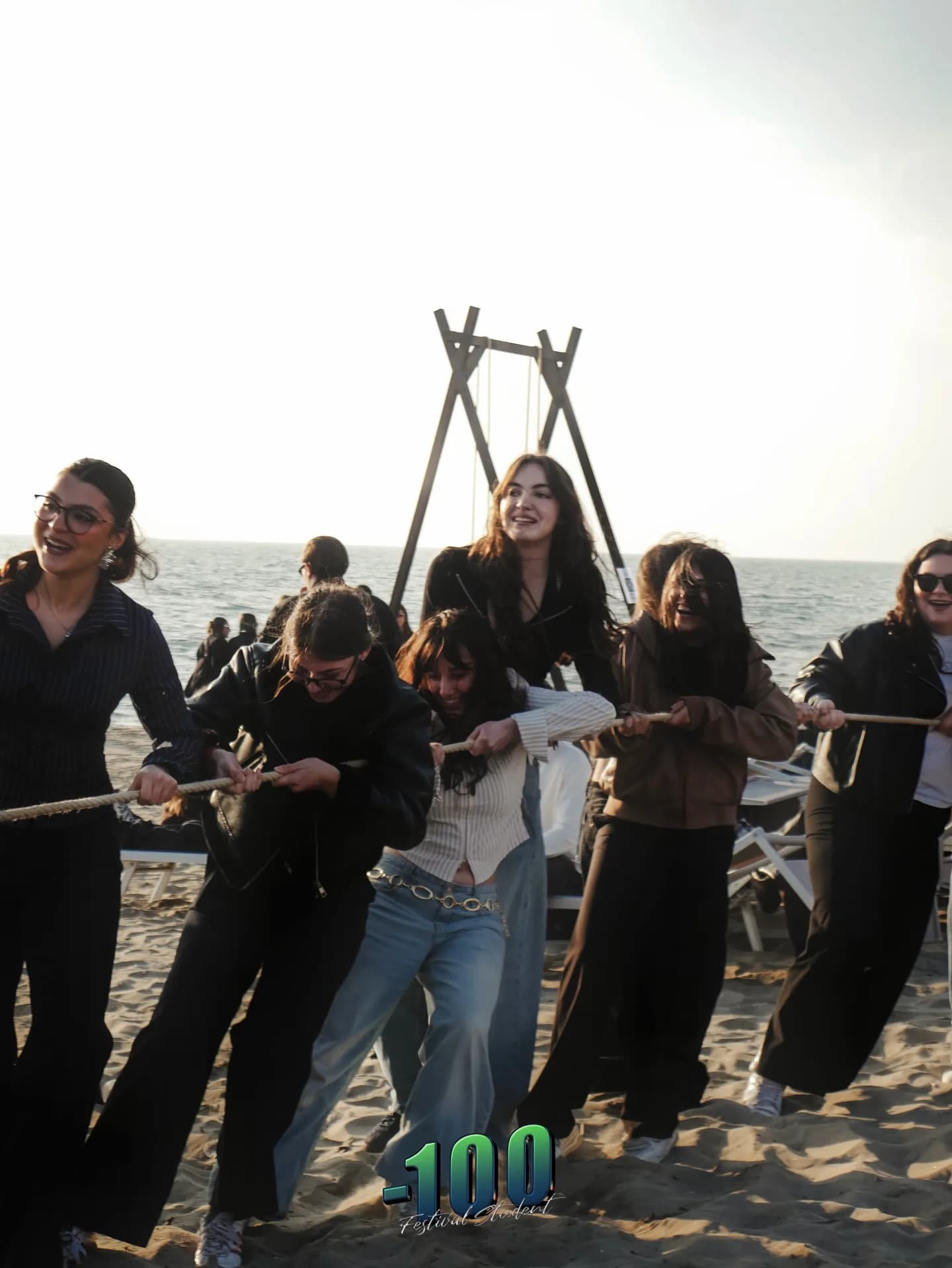 Un gruppo di ragazzi gioca sulla sabbia davanti al mare.